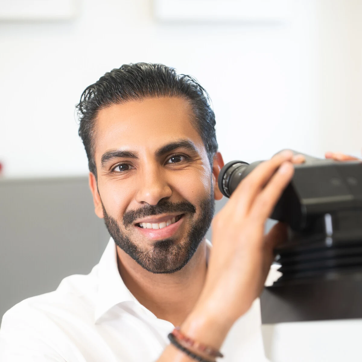Dr. Carlo De la Sancha smiling beside his microscope