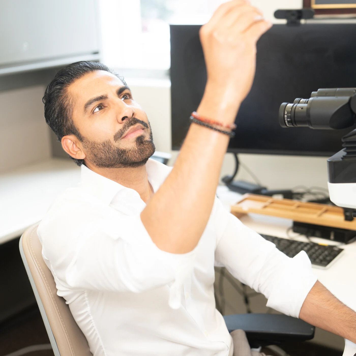 Dr. Carlo De la Sancha adjusting a microscope in his pathology office